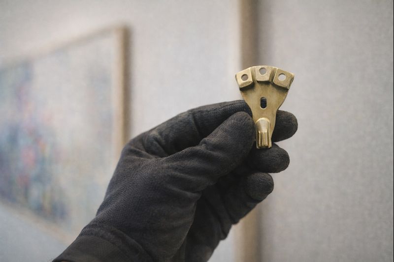 gloved hand of Proper Placement Studio team installing art hook